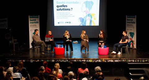 Un groupe sur une scène qui débat sur la santé mentale